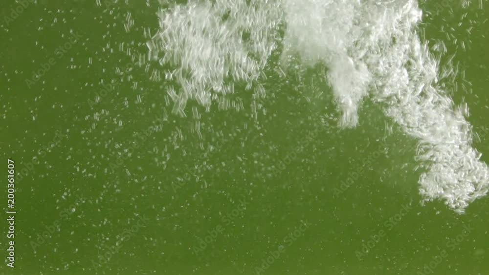 Stream of white bubbles in green water. Pouring water splashes and creates turbulent bubbles. Stream of white bubbles in green water. Pouring water splashes and creates turbulent bubbles.