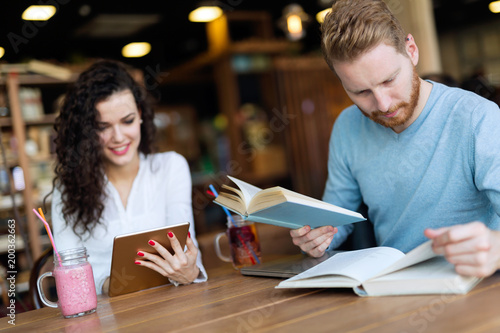 Young students spending time in coffee shop reading books