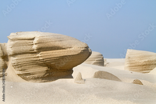 Wind erosion forms strange sculptures in the sand of a beach