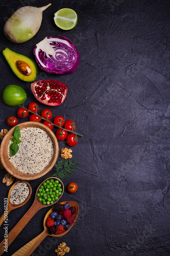 Selection of healthy food. Food background: quinoa, pomegranate, lime, green peas, berries, avocado, nuts and olive oil. Slate banner background. overhead, vertical