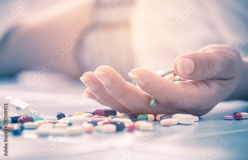 Overdose - close up of pills and addict. woman taking medicine overdose and lying on the wooden floor lying on the floor photo