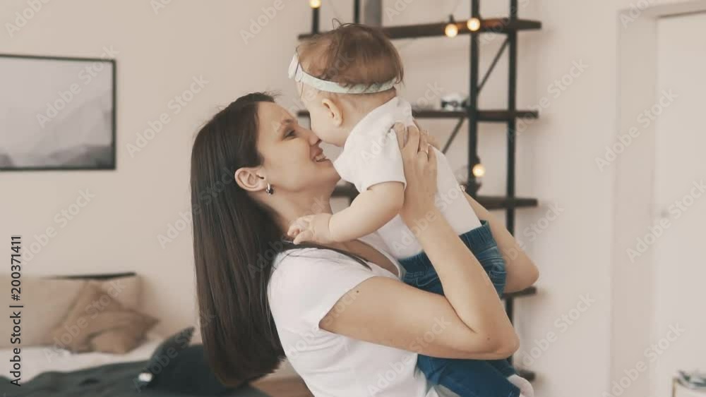 Little daughter in mother's arms at home. Smiling mother with child. Happy family and motherhood concept in slow motion Little daughter in mother's arms at home. Smiling mother with child. Happy family and motherhood concept in slow motion