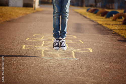 Closeup of boy's legs and playing hopscotch on playground outdoors. Hopscotch popular street game