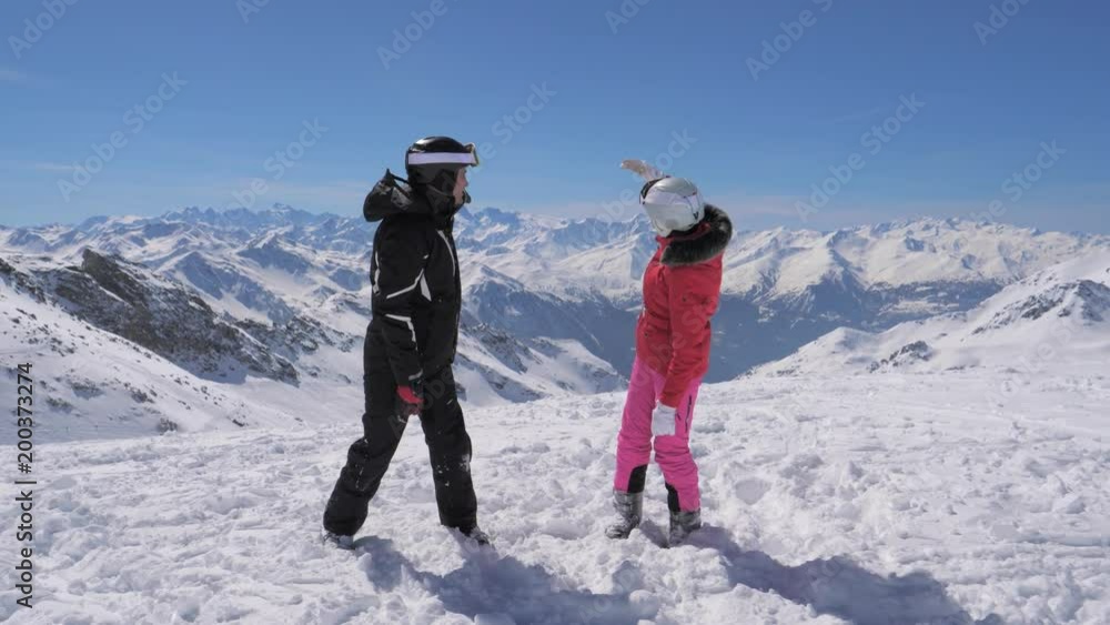 Happy couple of skiers standing on top of the mountain and looking back Happy couple of skiers standing on top of the mountain and looking back