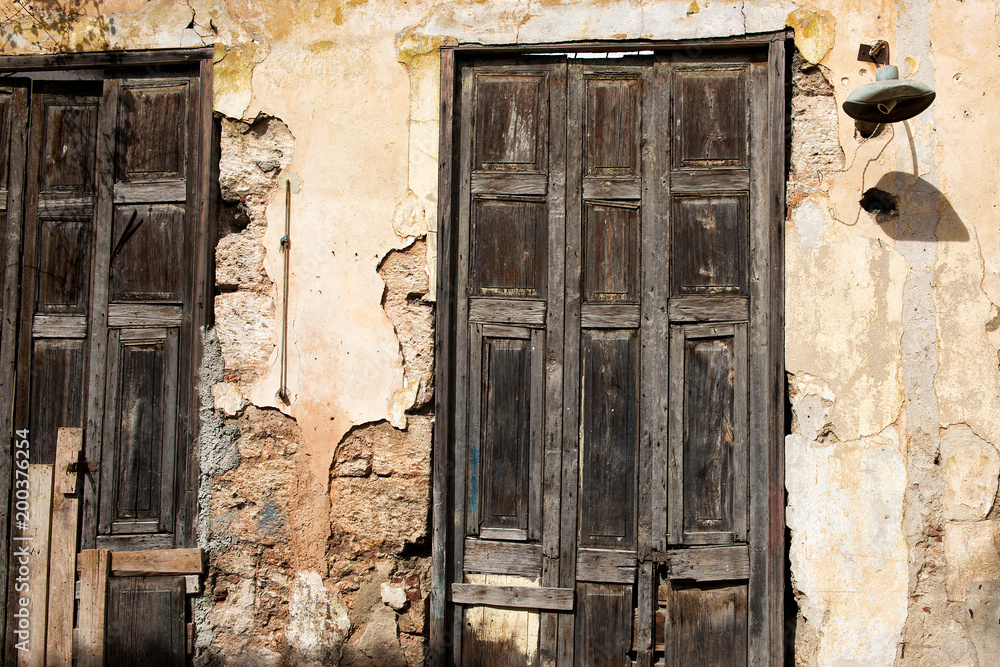 Naklejka premium Old doors with crumbling facade and antique lamp in Havana, Cuba