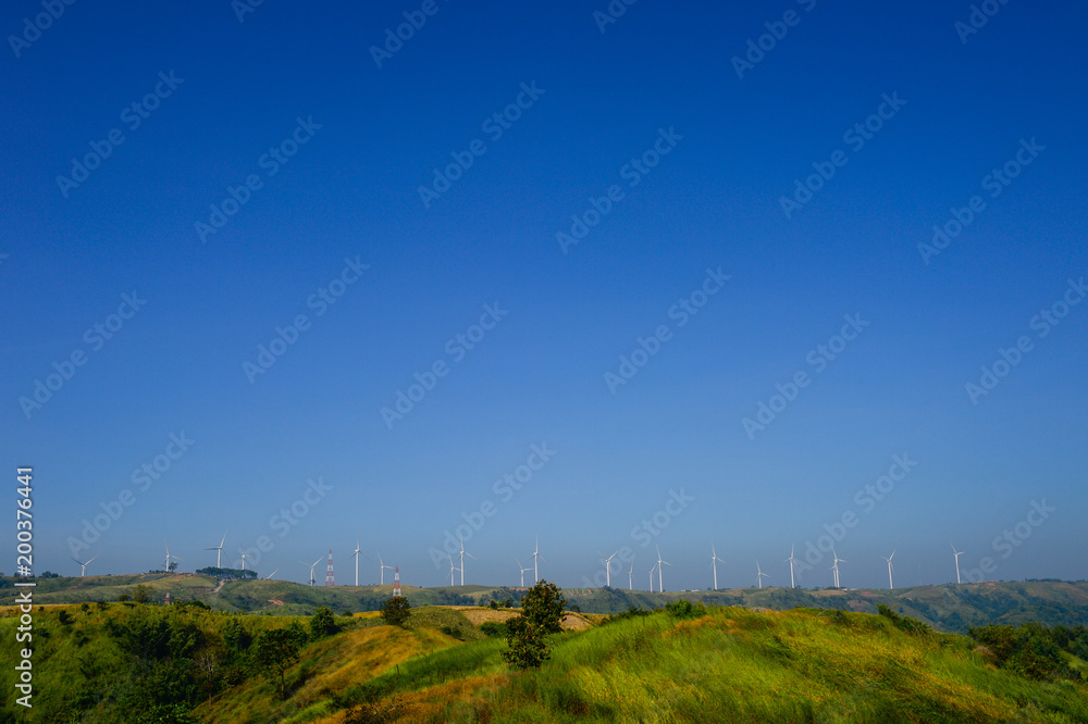 Windmills farm or Wind turbine power generators standing on green mountain against a blue sky, Located Khao Kho Phetchabun Province, Thailand