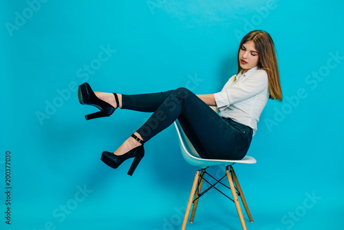 A young model poses on the camera in the studio. Stylish teenage girl. fashion clothes