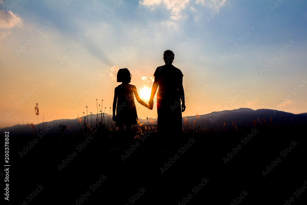 Silhouette mother with daughter looking sunset on mountain. Silhouette mother with daughter looking sunset on mountain.