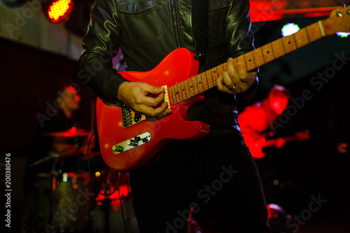 Closeup photo of bass guitar player hands, soft selective focus, bright live music theme