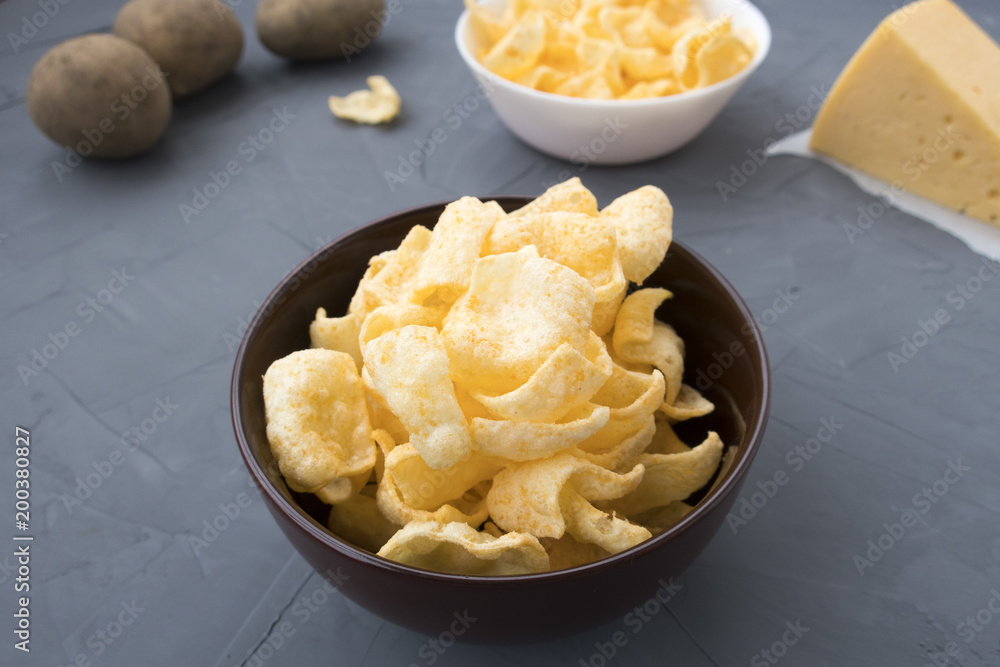 Potato chips with cheese in a plate that is located on a gray background. Potato chips with cheese in a plate that is located on a gray background.