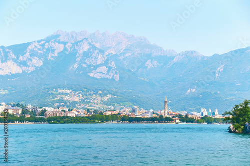 Beautiful summer view of the city of Lecco in Italy on the shore of lake Como with visible famous bell tower of the Basilica of San Nicolo. © berezko