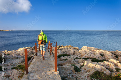A man in hat walks down the stairs to the sea