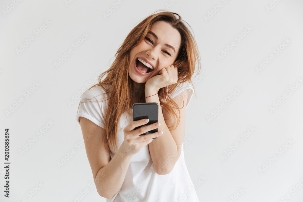 Naklejka premium Cheerful woman in casual clothes holding smartphone