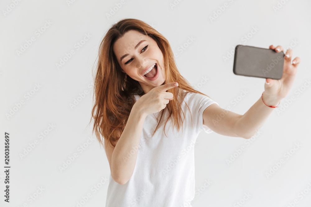 Naklejka premium Cheerful woman in casual clothes making selfie on smartphone
