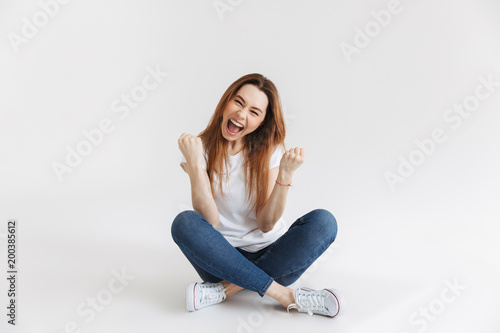 Cheerful screaming woman in t-shirt sitting on the floor