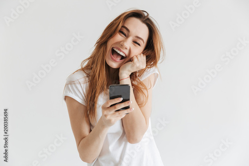 Cheerful woman in casual clothes holding smartphone