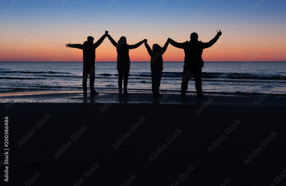 family silhouette on the beach after the sunset