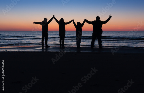 family silhouette on the beach after the sunset
