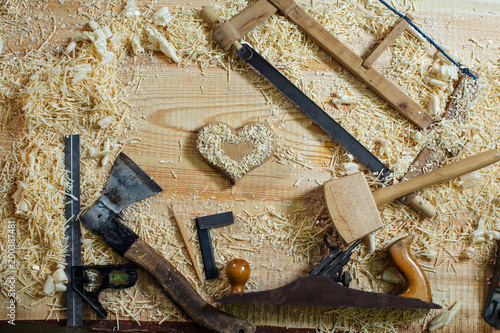 wooden heart on workbench and the tools with which it is made. woodworking, craftsmanship and handwork concept, flat lay