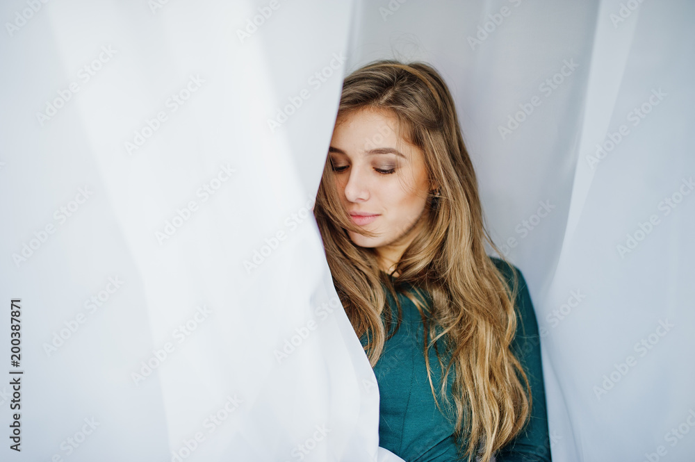 Handsome brunette girl wear on green, posing at curtains. Studio model portrait. Handsome brunette girl wear on green, posing at curtains. Studio model portrait.