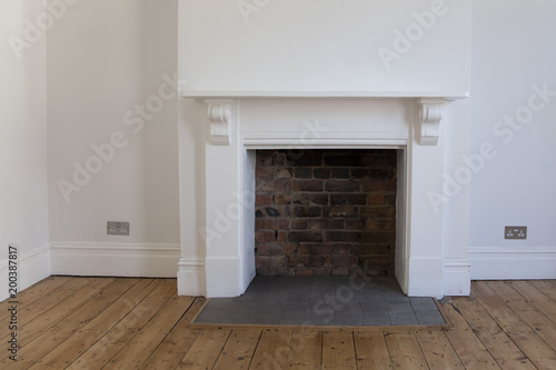 Victoriran wooden fireplace surround with white walls photo