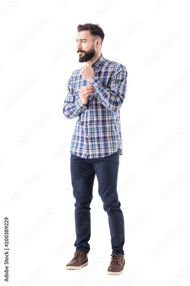 Cool bearded confident guy getting dressed buttoning sleeve button and looking away thoughtfully. Full body isolated on white background. Cool bearded confident guy getting dressed buttoning sleeve button and looking away thoughtfully. Full body isolated on white background.