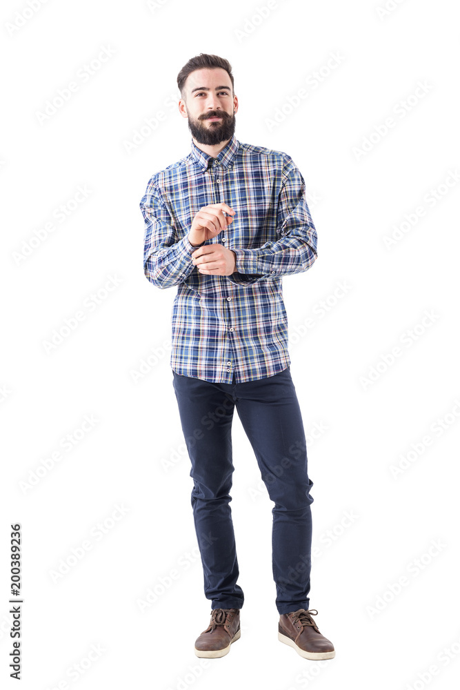Fototapeta premium Confident smiling bearded business man getting dressed buttoning sleeve and looking at camera. Full body isolated on white background. 