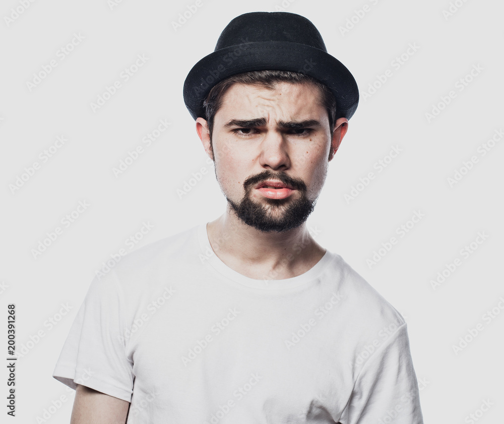 Portrait of bearded guy wearing black hat with unhappy expression on face Portrait of bearded guy wearing black hat with unhappy expression on face