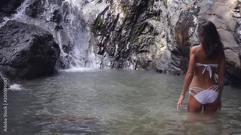Girl model posing on camera and beautifully enters the water near the waterfall. slow motion. 1920x1080. full hd Girl model posing on camera and beautifully enters the water near the waterfall. slow motion. 1920x1080. full hd