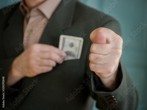 the man's hand shows the dolls and the other hand hides the banknotes of dollars in the jacket pocket