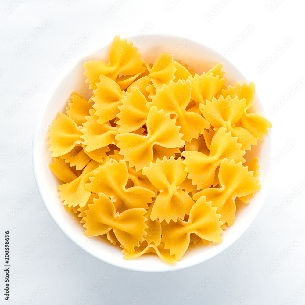 farfalle macaroni pasta in white bowl on white isolated background in the center close-up with top. farfalle macaroni pasta in white bowl on white isolated background in the center close-up with top.