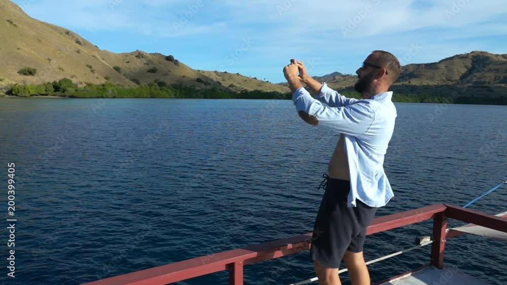 Young man taking photos with cellphone sailing yacht, super slow motion
Young man taking photos with cellphone sailing yacht, super slow motion