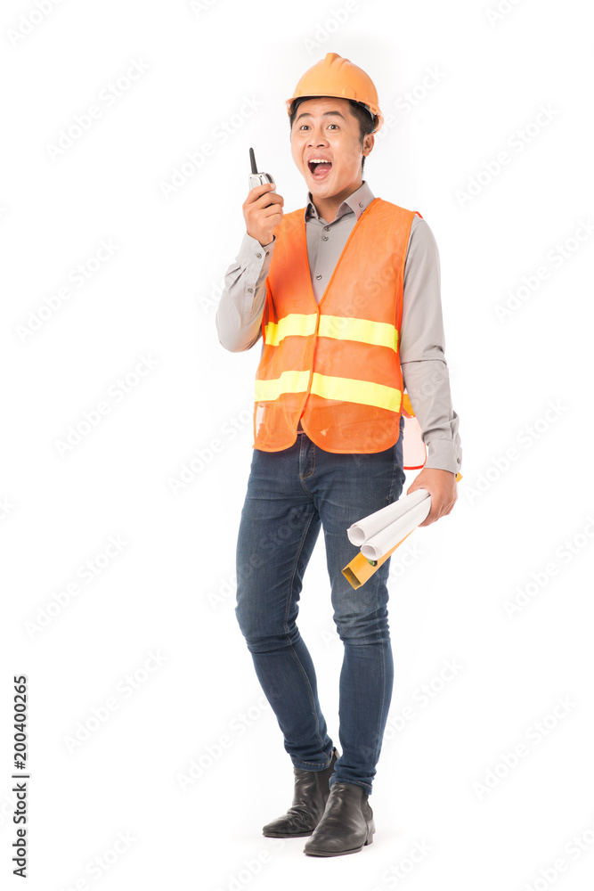 Studio portrait of construction worker in orange waistcoat and hardhat using walkie-talkie Studio portrait of construction worker in orange waistcoat and hardhat using walkie-talkie