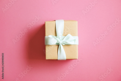 Single present wrapped in hand made craft paper gift wrap, tied w/ pastel satin bow. Simple giftbox, brown wrapping, giftwrap, blue ribbon. Holiday concept. Close up, background, copy space, top view.