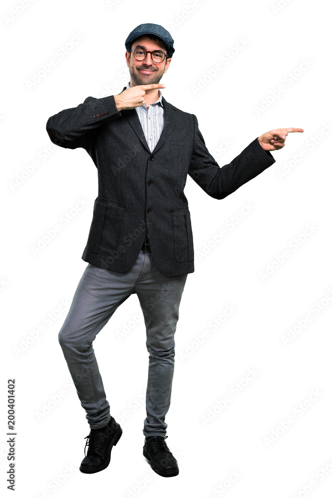Handsome modern man with beret and glasses pointing finger to the side and presenting a product Handsome modern man with beret and glasses pointing finger to the side and presenting a product