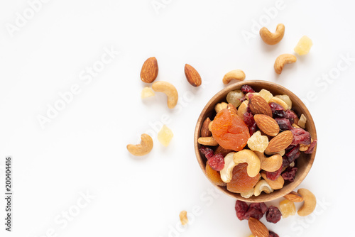 healthy snack: mixed nuts and dried fruits in wooden bowl on white background, almond, pineapple, cranberry, papaya, apple, strawberry, cherry, apricot, casshew.