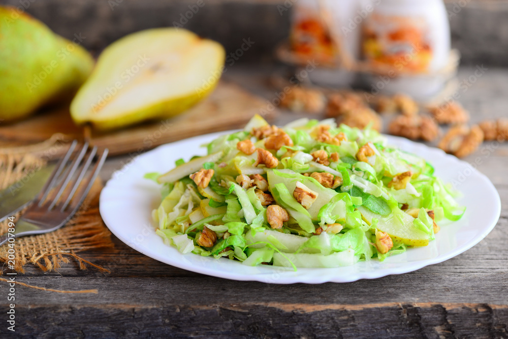 Pear and cabbage salad. Homemade salad with pear, cabbage and walnuts on a plate. Rustic wooden background. Quick healthy food. Closeup