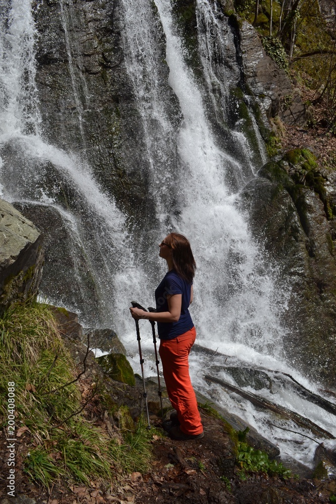 Naklejka premium Young woman admires the waterfall
