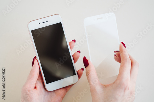 Smartphone with screen protect glass cover in hands. White background