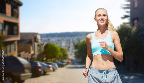 fitness, sport and healthy lifestyle concept - smiling woman running over san francisco city background