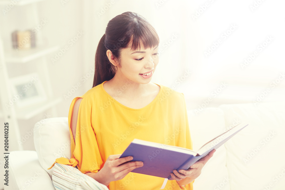 leisure, literature and people concept - smiling young asian woman reading book at home leisure, literature and people concept - smiling young asian woman reading book at home