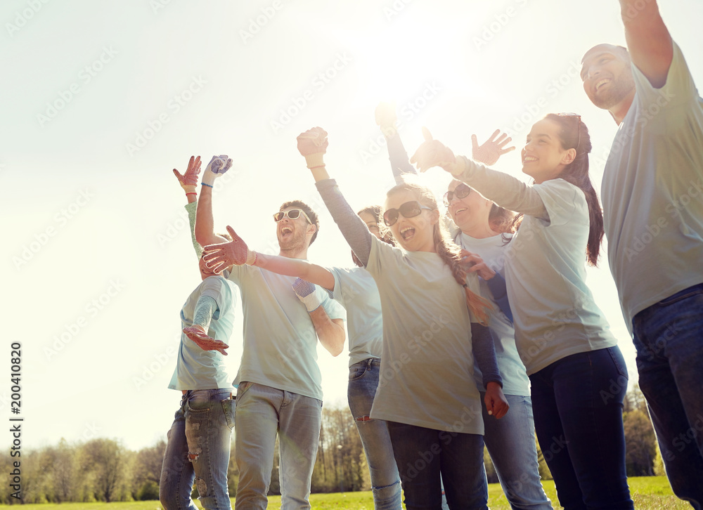 volunteering, charity and people concept - group of happy volunteers celebrating success up in park volunteering, charity and people concept - group of happy volunteers celebrating success up in park