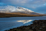 Reflection of mountain peak covered by snow in frozen lake at Arran island, Scotland