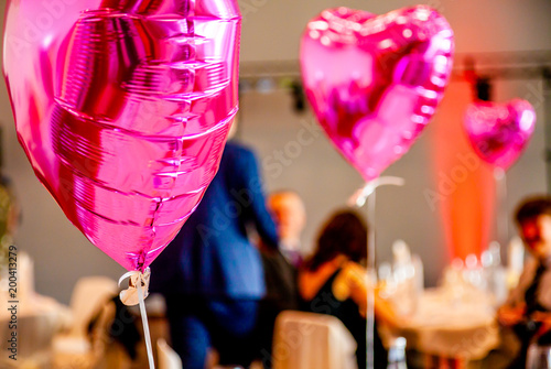 Pink festive balloons shape of heart with the party guests in the background photo
