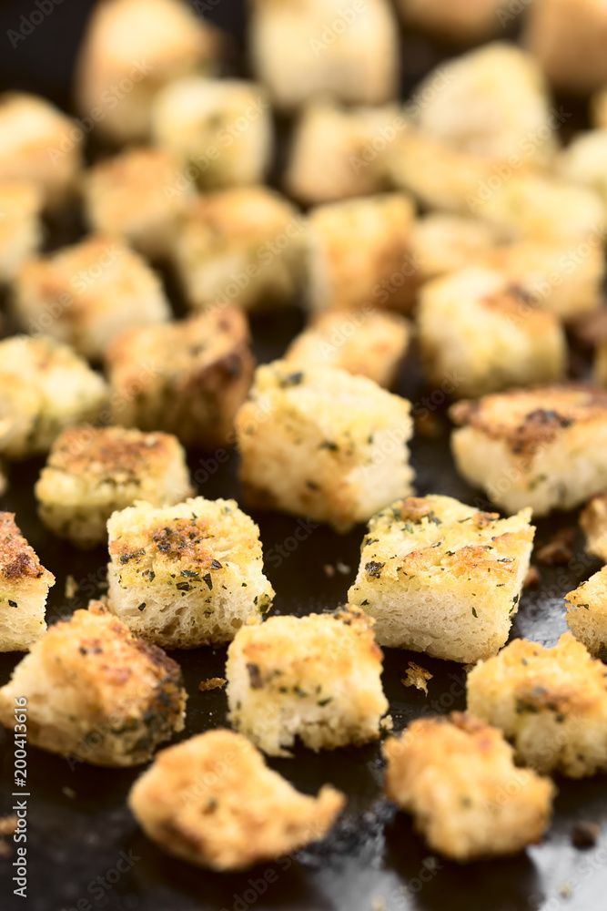 Freshly baked crunchy croutons seasoned with herbs on baking tray (Selective Focus, Focus one third into the image) Freshly baked crunchy croutons seasoned with herbs on baking tray (Selective Focus, Focus one third into the image)