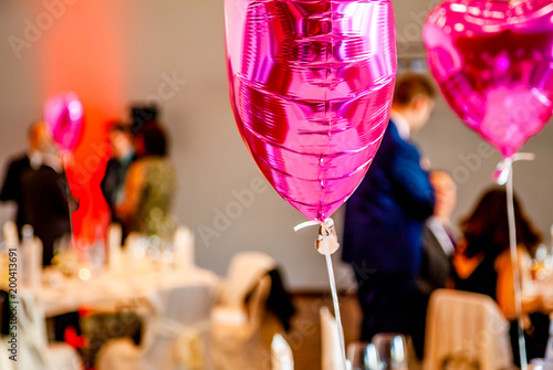 Pink festive balloons shape of heart with the party guests in the background photo