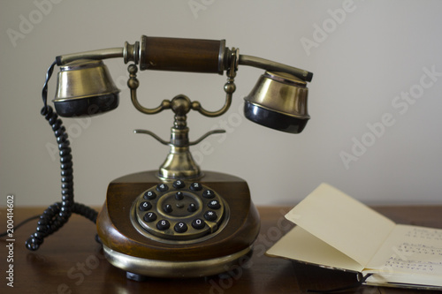 Vintage phone on wooden table and open phonebook on the side