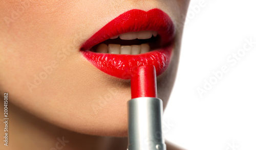 beauty, make up and cosmetics concept - close up of face of woman applying red lipstick to her lips over white background