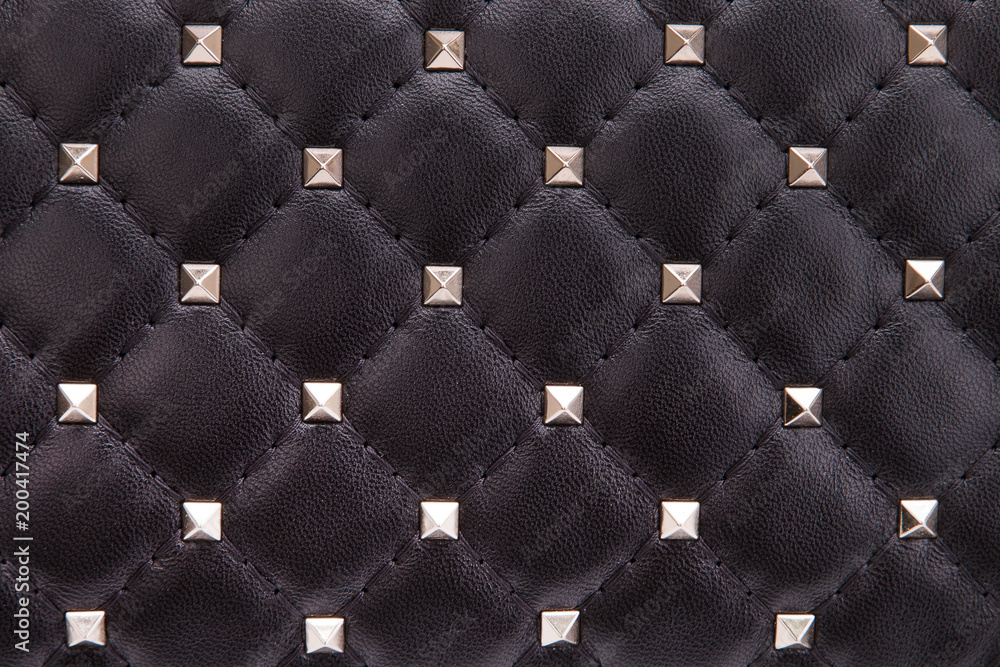 Obraz premium Fragment of black leather with metal spikes