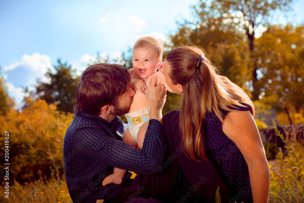 Fototapeta premium Mom and Dad kiss their son to laugh